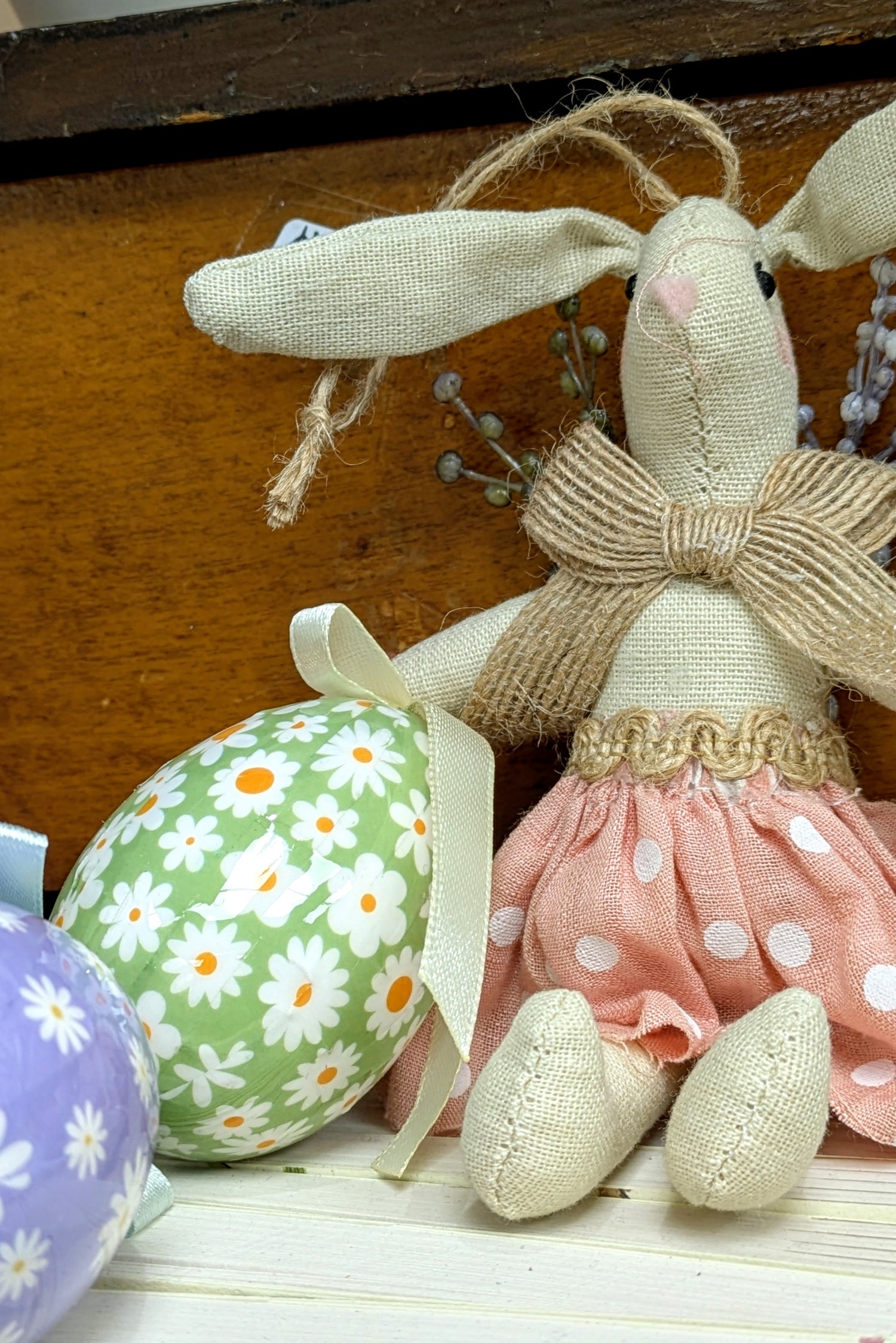 Decorative Easter bunny with a pink dress and floral eggs on a wooden surface