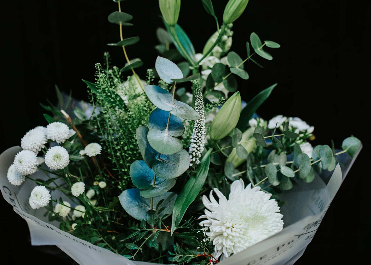 A hand-tied bouquet of white flowers and greenery, presented in eco-friendly biodegradable wrapping.